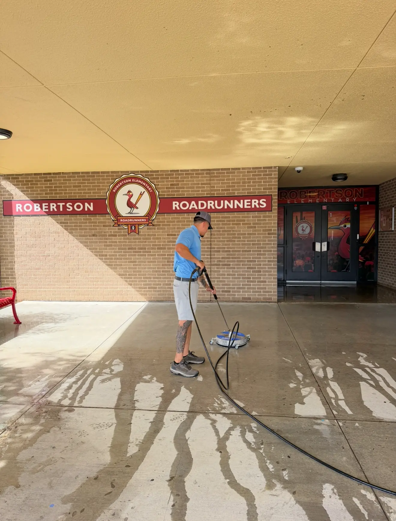 FTF crew member pressure washing a concrete walkway at Robertson Elementary in Austin Texas