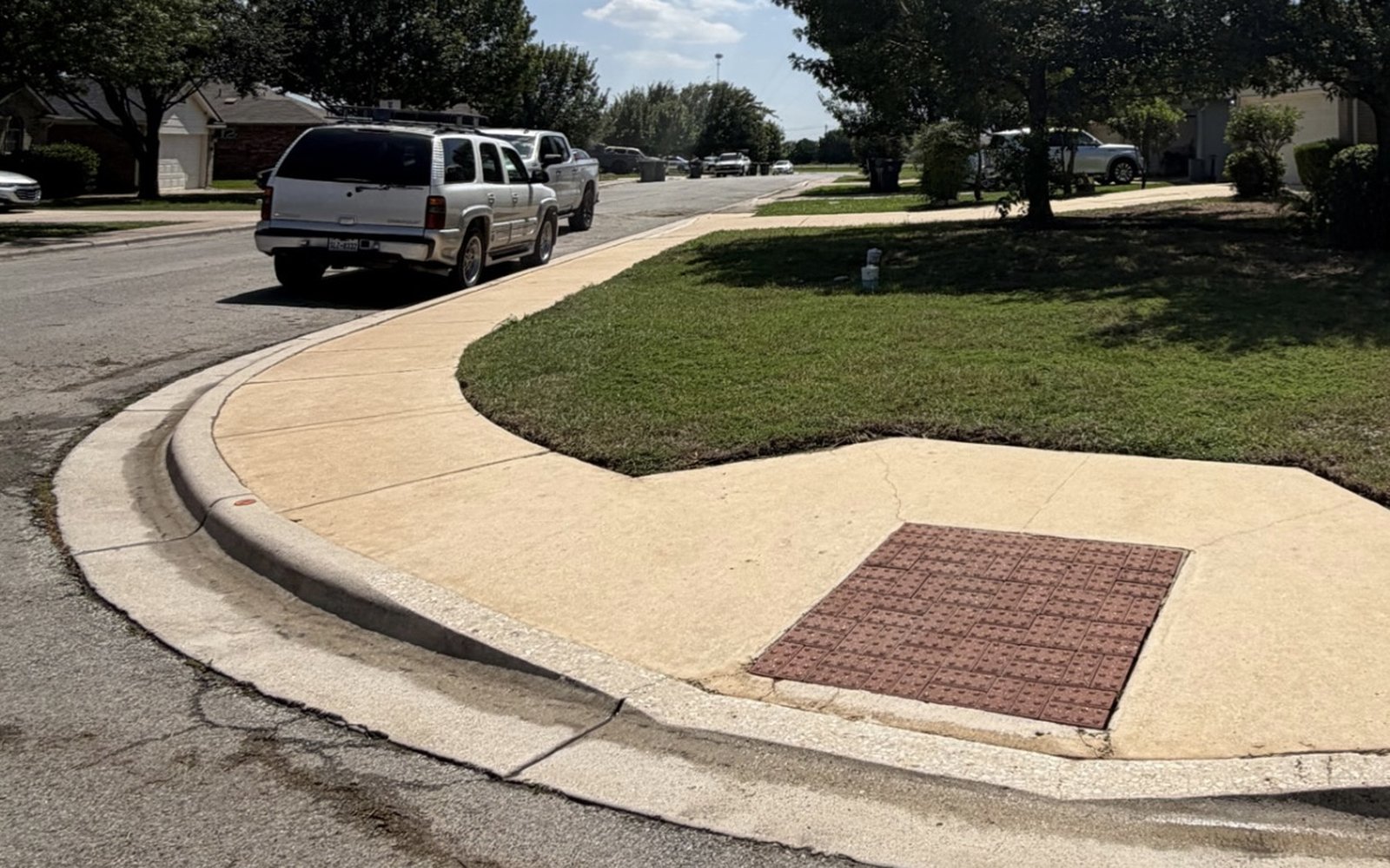 The same neighborhood sidewalk and corner pad near Austin TX after pressure washing, cleaned edge to edge