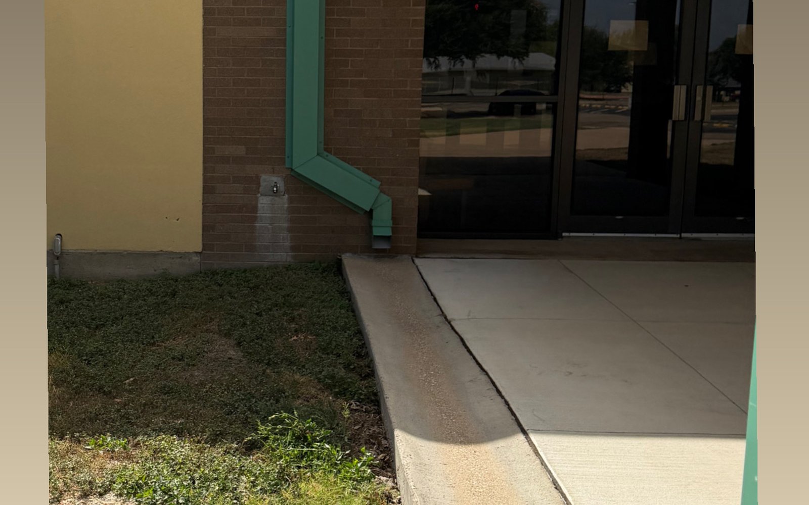 The same storefront entry concrete in the Austin TX area after commercial pressure washing, with even light-grey concrete