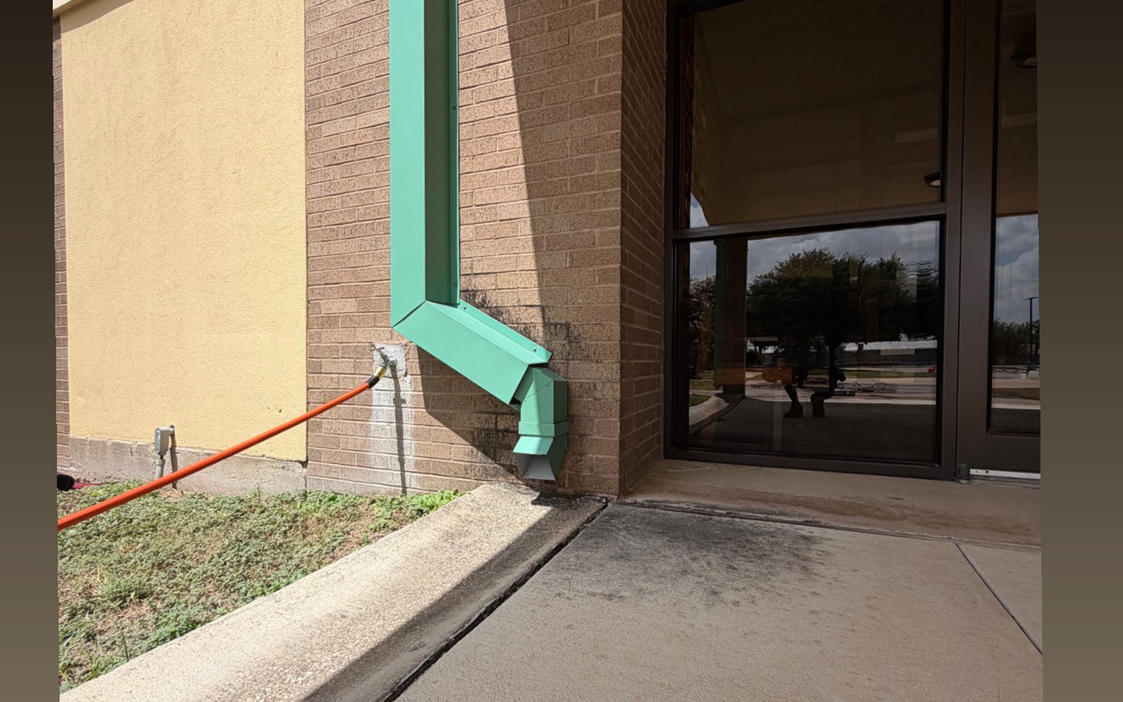 Stained concrete entry outside a Greater Austin TX storefront before commercial pressure washing